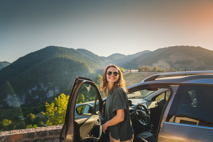 Woman getting out of her car overlooking a mountain view